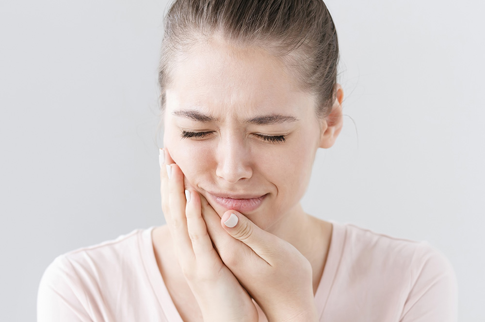 Woman holding her jaw with a painful expression.